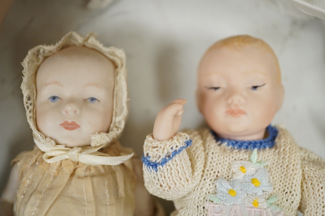 A large jointed bisque head doll and two miniature bisque dolls
